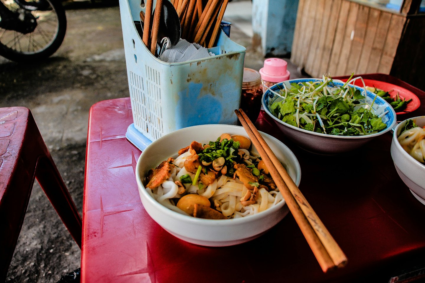A bowl of noodle soup with meat and mushrooms on a table.