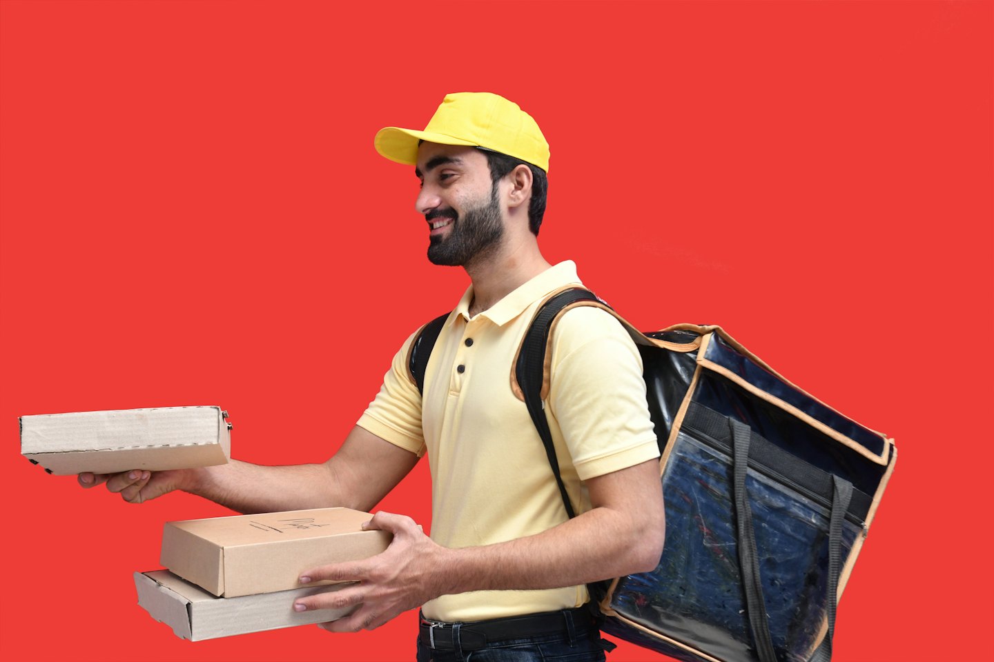 Delivery driver holds brown packages with a red background.