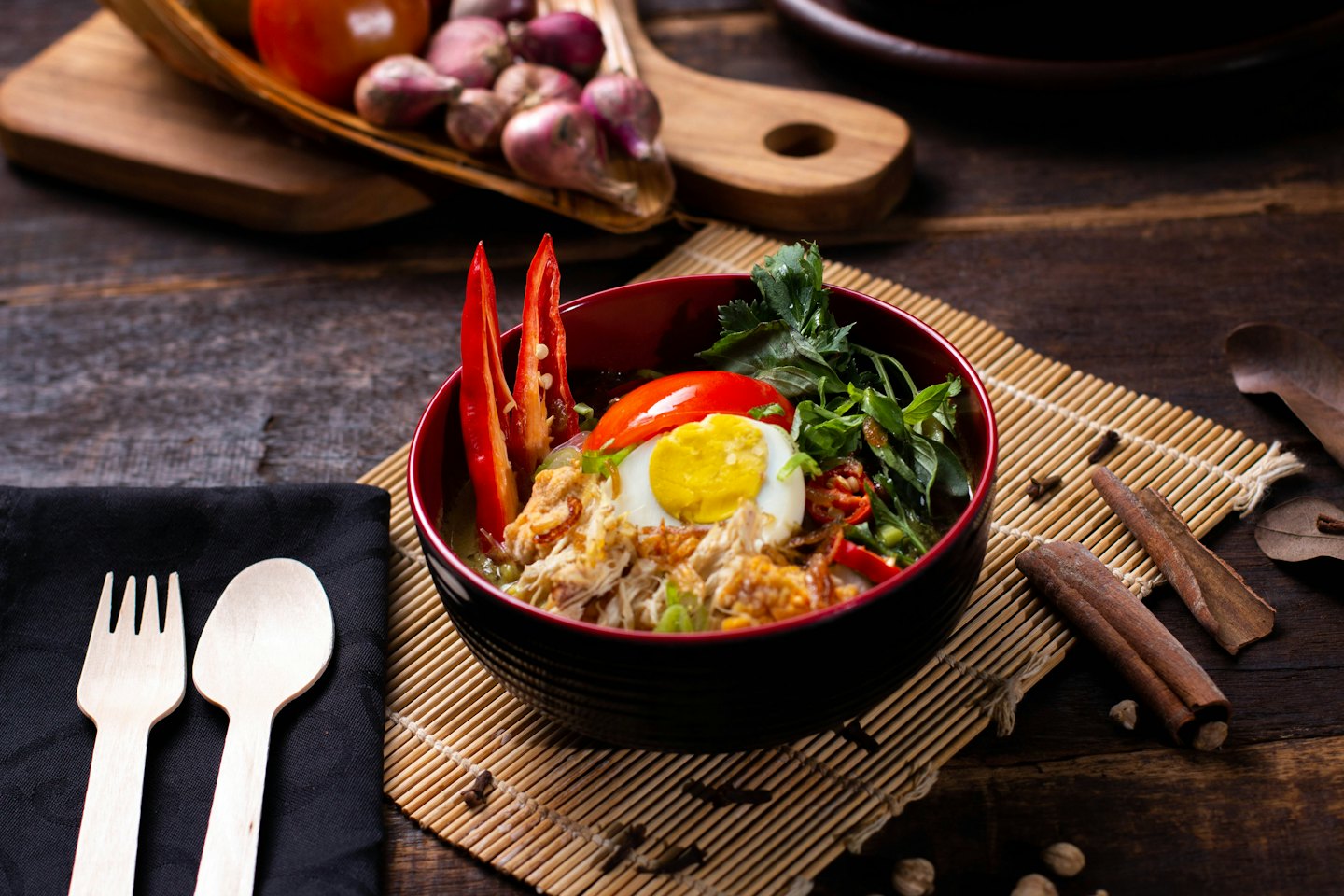 A bowl of Indonesian soto soup topped with egg and herbs.