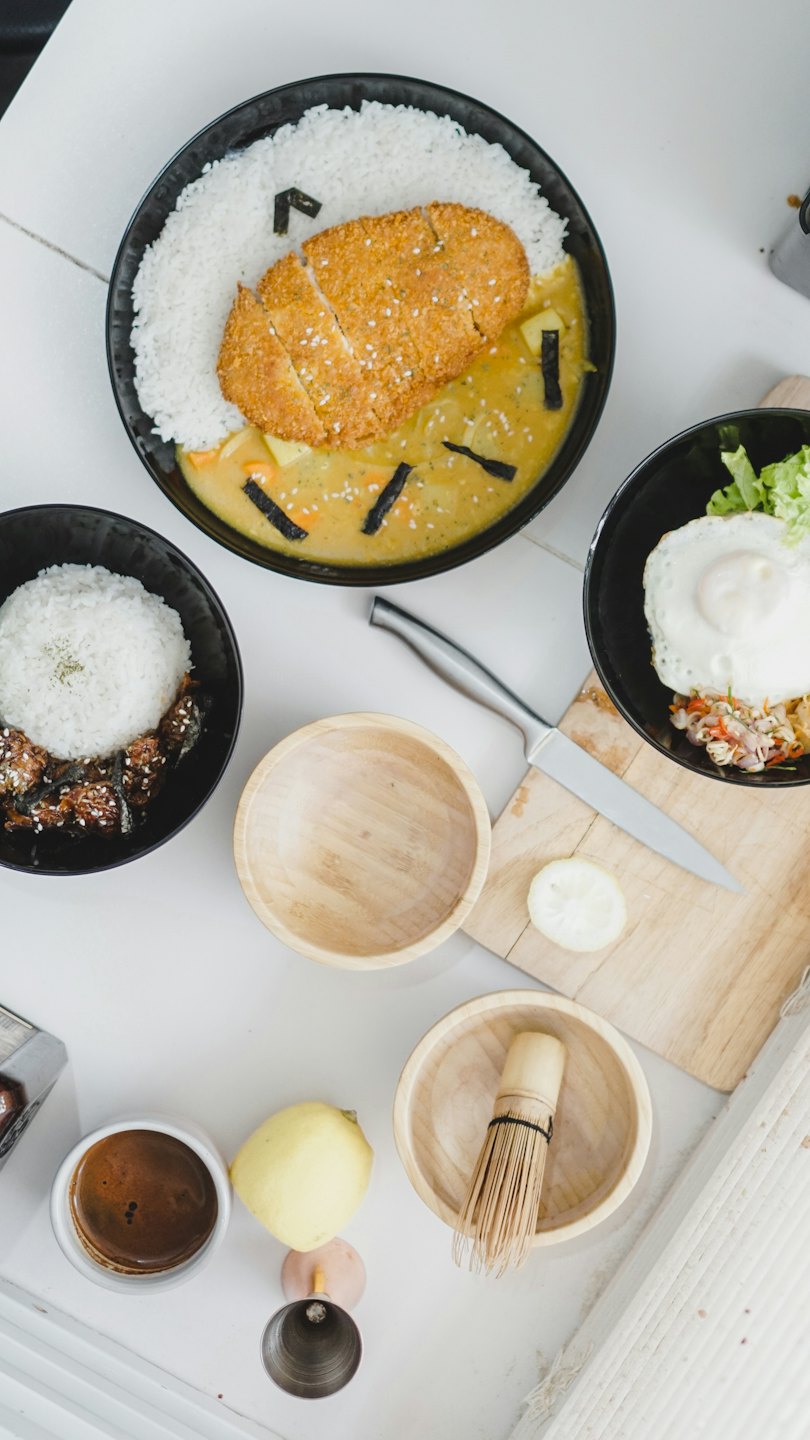 Three Asian inspired rice bowls arranged on a tiled countertop.