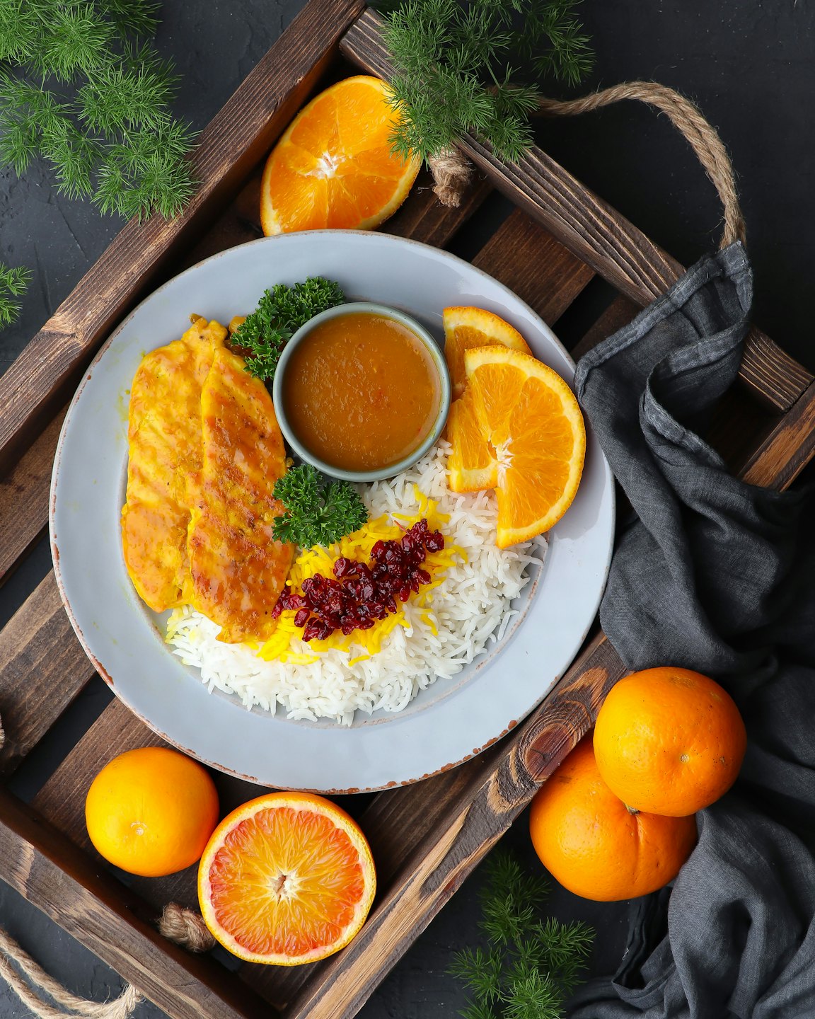 Turmeric chicken with rice and sauce served on a wooden tray.